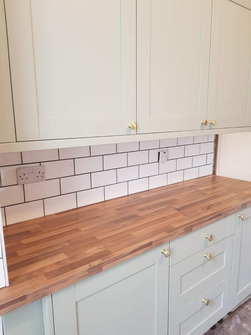 Sage green shaker kitchen with brass knobs and oak worktop, fitted by Handi-Work